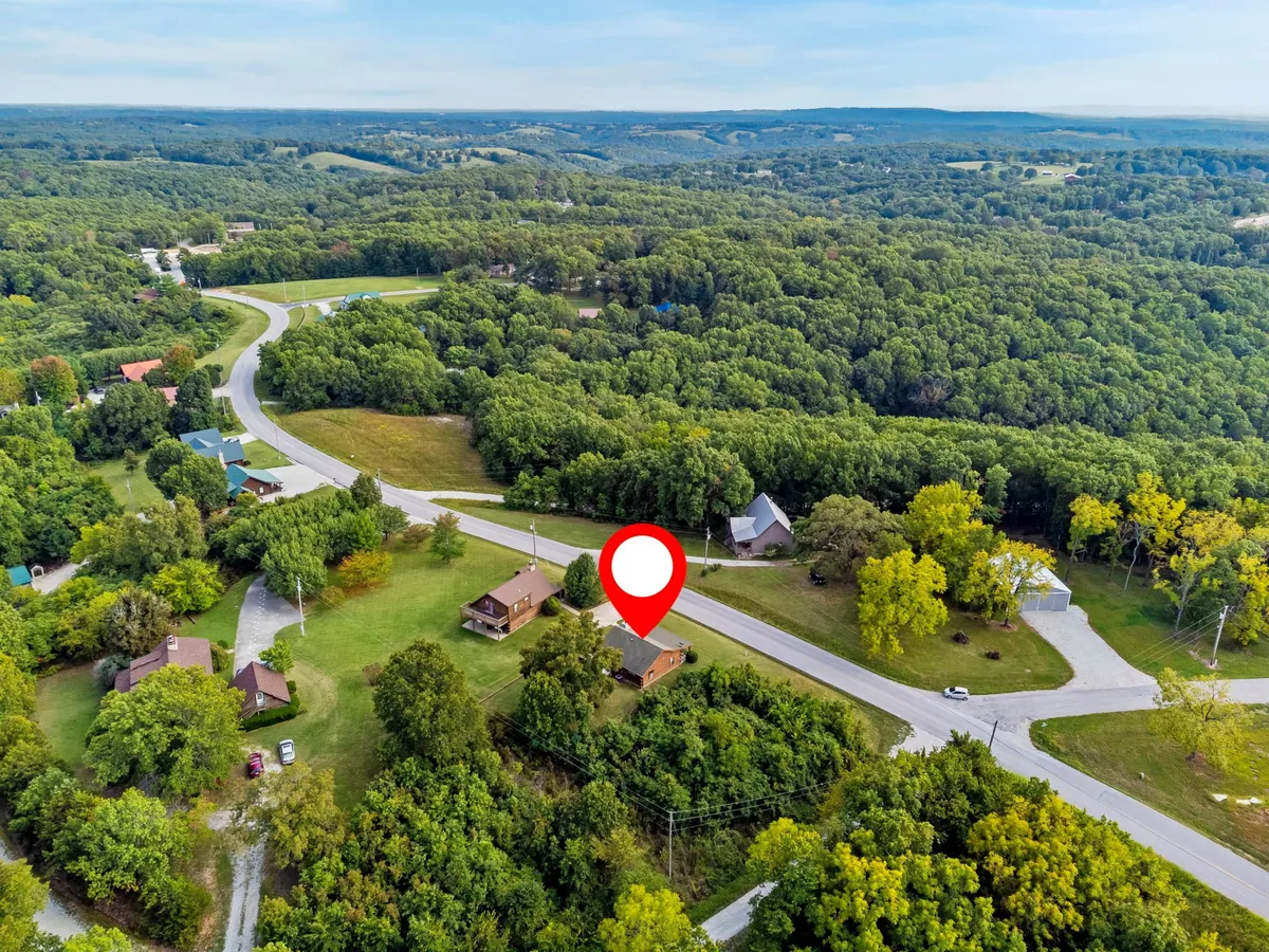 A picturesque exterior showcasing the highlighted house nestled in greenery, with a winding road leading to the property. The setting is peaceful and secluded, offering views of the surrounding hills and plenty of space for outdoor enjoyment, including watching sunsets and stargazing.