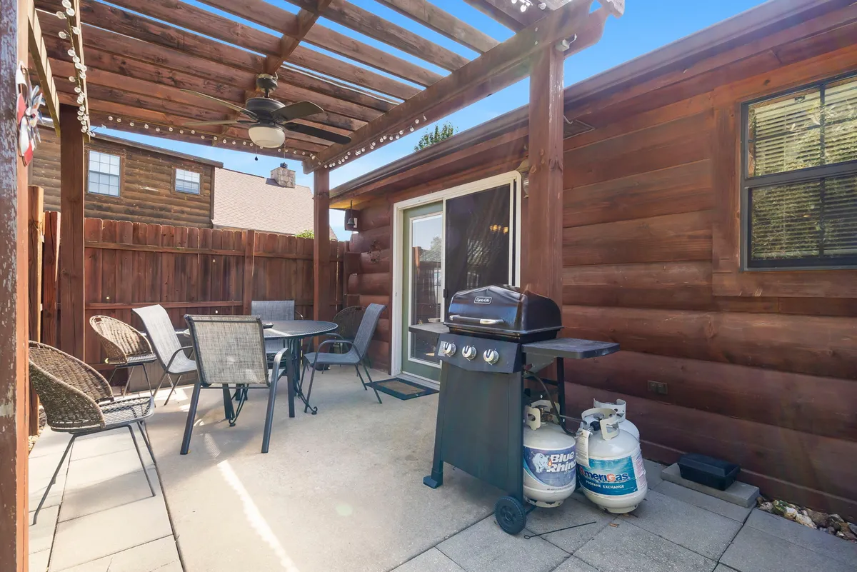 An outdoor scene with a gas grill, dining table under a pergola, and a fenced yard—perfect for barbecues and outdoor dining. The setting appears inviting for social gatherings, relaxation, and enjoying meals in the fresh Ozarks air.