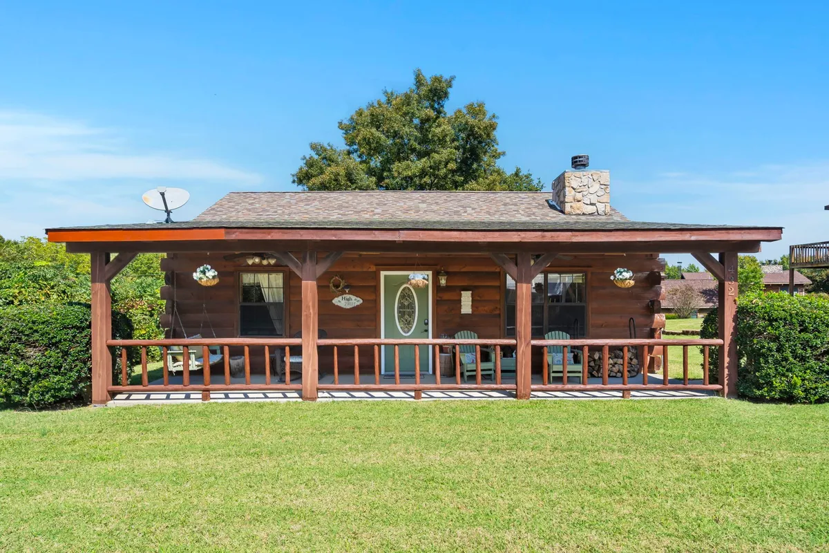 A welcoming view of the wooden porch and stone chimney, bordered by a green lawn. It suggests a cozy, inviting entrance that merges indoor comfort with the scenic outdoors, perfect for returning from a hike with your pup.