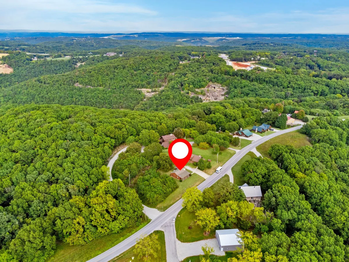This image features the main house set amongst mature trees and surrounded by open green space. Roadways and paths hint at accessibility for outdoor activities like hiking and nature walks. The peaceful atmosphere is emphasized by the natural landscape.
